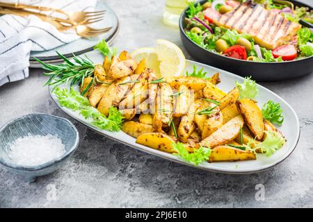 Kartoffelkeile, im Ofen gebraten mit frisch gemischtem Salat und gegrilltem Käse Stockfoto