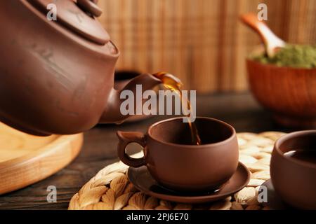 Teezeremonie. Traditionelles Asiatisches Teeutensil, Serviert Authentisches Set. Person, die Tee von der Teekanne aus brauner Keramik bis zur Teekanne einschenkt. Bambusschale. Lifestyle. Wir Stockfoto