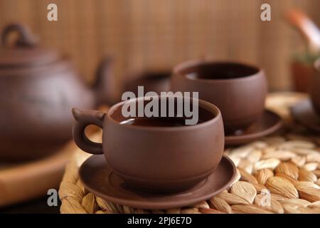 Teezeremonie. Traditionelles Asiatisches Teeutensil, Serviert Authentisches Set. Person, die Tee von der Teekanne aus brauner Keramik bis zur Teekanne einschenkt. Bambusschale. Lifestyle. Wir Stockfoto