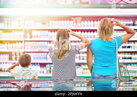 Mutter und Kinder wählen Milchprodukte im Geschäft aus Stockfoto