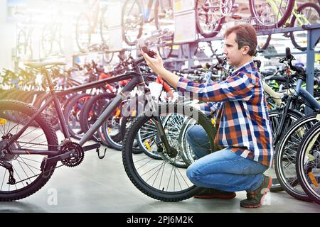 Ein Mann überprüft das Fahrrad, bevor er in einem Sportgeschäft einkauft Stockfoto