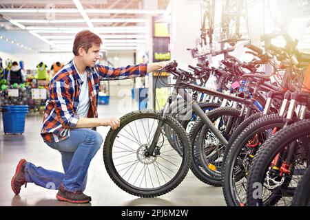 Ein Mann überprüft das Fahrrad, bevor er in einem Sportgeschäft einkauft Stockfoto