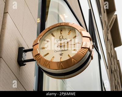 Omega beobachtet die Uhr an einer Fassade. Schweizer Luxusuhrmacher macht Werbung in der Einkaufsstraße. Die Marke Omega Constellation ist teuer. Stockfoto