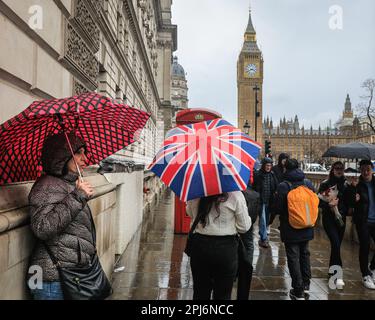 London, Großbritannien. 31. März 2023. Londoner und Touristen bekommen ihre Schirme raus, während sie einen Spaziergang durch die Westminster Sehenswürdigkeiten im Zentrum von London machen, an einem Tag, der meist grau und sehr regnerisch in der Hauptstadt war. Kredit: Imageplotter/Alamy Live News Stockfoto
