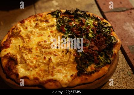 Eine leckere Pizza mit Käse und anderen verschiedenen Belägen, serviert auf einem Teller Stockfoto