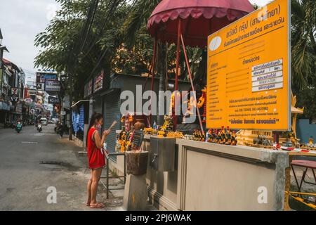 Pattaya, Thailand - Oktober 15,2022: Soi Buakhao Eine junge Thai-Frau betete vor einem kleinen buddhistischen Schrein. Stockfoto