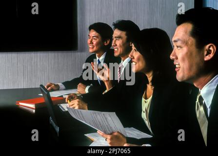 1996 HISTORISCHE ASIATISCHE BÜROANGESTELLTE TREFFEN SICH AM TISCH Stockfoto