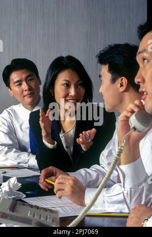 1996 HISTORISCHE ASIATISCHE BÜROANGESTELLTE TREFFEN SICH AM TISCH Stockfoto