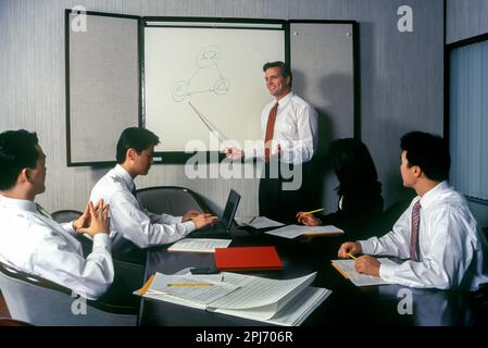 1996 HISTORISCHE ASIATISCHE EUROPÄISCHE BÜROANGESTELLTE TREFFEN SICH AM TISCH Stockfoto