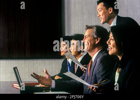 1996 HISTORISCHE ASIATISCHE EUROPÄISCHE BÜROANGESTELLTE TREFFEN SICH AM TISCH Stockfoto