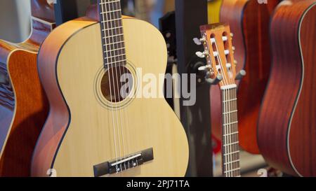 Klassische Gitarren in einem Instrumentenladen, an einer Wand aufgehängt, Nahaufnahme. Stockfoto