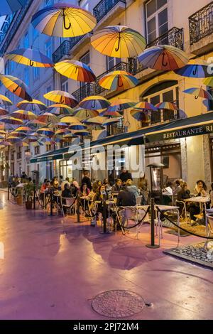 Europa, Portugal, Lissabon. 18. April 2022. Farbenfrohe Sonnenschirme über Cafés an einer Fußgängerzone in Lissabon. Stockfoto