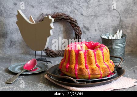Orangefarbener Vanillekuchen mit pinkfarbenem Glasur, Osterdekor. Stockfoto