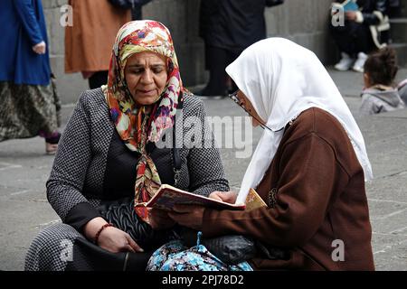 Eine Frau wird dabei gesehen, wie sie einer anderen Frau beim Besuch der Schreine in Diyarbakir zuhört, die den Koran rezitiert. Im Monat Ramadan besuchen Sie heilige Stätten und Schreine, beten und wünschen sich etwas. Einer dieser heiligen Stätten ist die Hazrat Suleyman Moschee, die 1150 erbaut wurde und eines der wichtigsten religiösen und touristischen Zentren der Moslems der Welt ist. Im Garten der Moschee gibt es Schreine von 27 Menschen, die hier während der Ausbreitung des Islam starben und angeblich Nachkommen des Propheten (Sahaba) Mohammed waren. Diejenigen, die die Schreine besuchen, den Koran lesen, beten und Wünsche äußern. Stockfoto