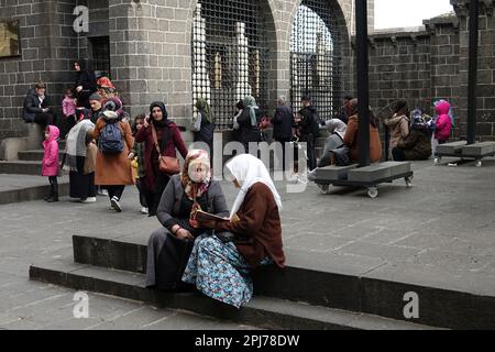 Eine Frau wird dabei gesehen, wie sie einer anderen Frau beim Besuch der Schreine in Diyarbakir zuhört, die den Koran rezitiert. Im Monat Ramadan besuchen Sie heilige Stätten und Schreine, beten und wünschen sich etwas. Einer dieser heiligen Stätten ist die Hazrat Suleyman Moschee, die 1150 erbaut wurde und eines der wichtigsten religiösen und touristischen Zentren der Moslems der Welt ist. Im Garten der Moschee gibt es Schreine von 27 Menschen, die hier während der Ausbreitung des Islam starben und angeblich Nachkommen des Propheten (Sahaba) Mohammed waren. Diejenigen, die die Schreine besuchen, den Koran lesen, beten und Wünsche äußern. Stockfoto