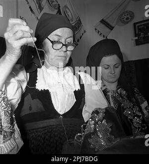 Sibiu County, Rumänien, ca. 1977. Eine Gruppe von Frauen verschiedener Generationen, die traditionelle folkloristische Kleidung von Hand nähen. Stockfoto