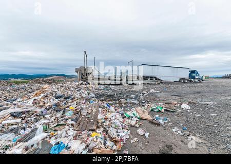 Großes Bohrfahrzeug mit Auflieger auf Anhänger-Kipper auf einer aktiven Deponie. Stockfoto