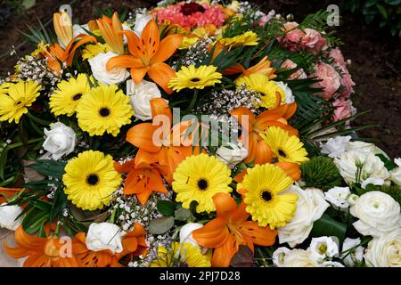 Weiße Rosen, gelbe Gerbera und Feuerlilien als Beileidsblumen auf einer Beerdigung Stockfoto