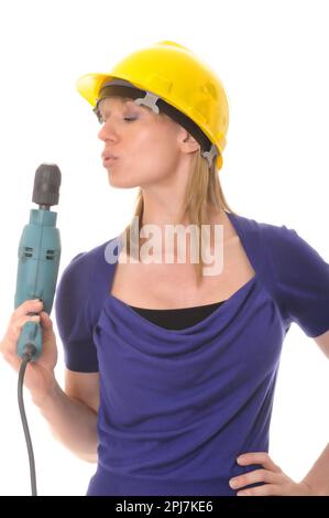 Ein blondes Mädchen, das einen Elektrobohrer hält und einen Schutzhelm trägt Stockfoto