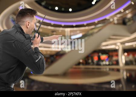 Männlicher Wachmann mit tragbarem Funksender im Einkaufszentrum Stockfoto