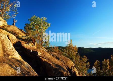 Eine junge Frau fotografiert die Aussicht vom Gipfel des Breakneck Ridge nach einer Wanderung auf den Gipfel der Hudson Highlands von New York Stockfoto