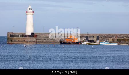 Boote am Hafenkai und weißer Leuchtturm an der Ostküste Nordirlands im Donaghadee County Down Northern Ireland am sonnigen Frühlingstag. Stockfoto