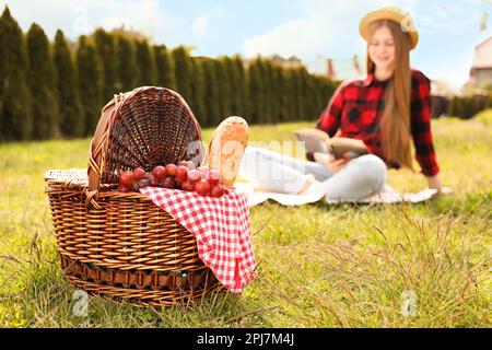 Mädchen liest Buch im Park, konzentriert euch auf den Korb Stockfoto