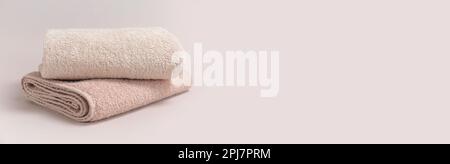 Zwei gefaltete beige Handtücher auf hellem Hintergrund, Platz für Text. Bannerdesign Stockfoto