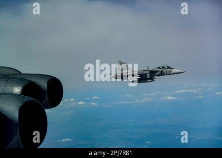 Ein ungarischer Luftwaffe Saab JAS 39 Gripen fliegt in Formation mit einer B-52H Stratofestung, die der 23. Expeditionsbombenstaffel im Zuständigkeitsbereich der europäischen Kommandozentrale der Vereinigten Staaten vom 22. März 2023 zugeteilt wurde. Missionen der Bomber-Task Force machen die Flugbesatzung mit den Luftstützpunkten und Operationen in verschiedenen geografischen Einsatzgebieten der Kämpfer vertraut. (USA Air Force kostenloses Foto) Stockfoto