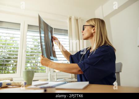 Arztin im Röntgenbild des Patienten während der Sprechstunde am Arbeitsplatz Stockfoto