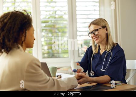 Der Arzt misst die Temperatur des Patienten während eines Arzttermins mit einem berührungslosen Thermometer Stockfoto