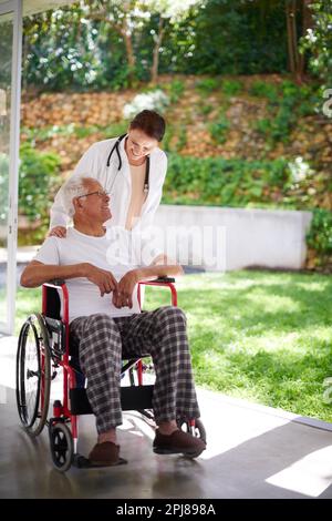 Positive Unterstützung für ältere Patienten. Die volle Länge eines Seniorenmannes im Rollstuhl, der mit seinem Arzt spricht. Stockfoto