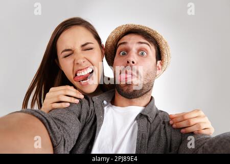 Ich fühle mich albern. Selbstporträt eines glücklichen jungen Ehepaars im Studio, das dumme Gesichter zieht. Stockfoto