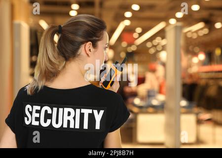 Weiblicher Wachmann in Uniform mit tragbarem Funksender im Einkaufszentrum Stockfoto