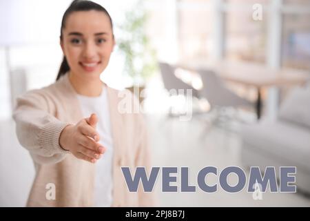 Fröhliche junge Frau, die drinnen Handschlag gibt, konzentriere dich auf die Hand. Willkommen im Team Stockfoto