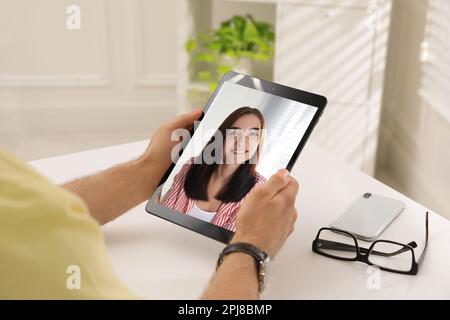 Ein Mann, der mit einer schönen Frau spricht, per Video-Chat auf einem Tablet am weißen Tisch, Nahaufnahme. Online-Dating Stockfoto