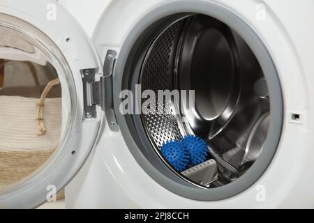 Blaue Trocknerkugeln in der Waschmaschinentrommel Stockfoto