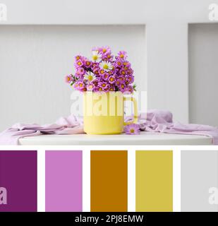 Becher mit wunderschönen Blumen und Tuch auf weißem Tisch. Komposition inspiriert von den Farben des Jahres 2021 Stockfoto