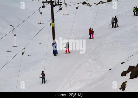 Skilift in Betrieb mit mehreren Skifahrern, die bergauf fahren Stockfoto