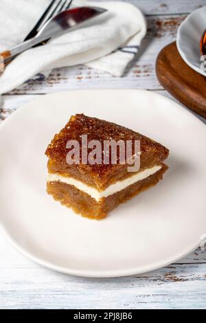 Brotpudding auf Holzboden. Traditionelles Ramadan-Dessert. Brot Kadayif mit Sahne in der Mitte. Lokaler Name Kaymaklı ekmek kadayifi Stockfoto