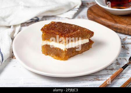 Brotpudding auf Holzboden. Traditionelles Ramadan-Dessert. Brot Kadayif mit Sahne in der Mitte. Lokaler Name Kaymaklı ekmek kadayifi Stockfoto