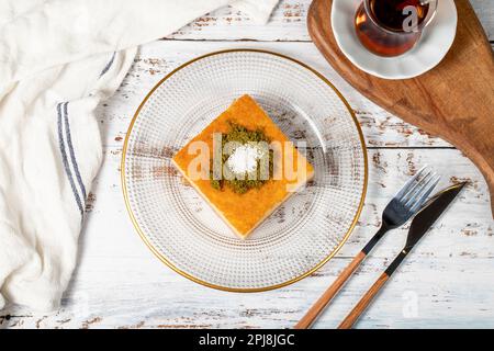 Revani-Dessert auf Holzhintergrund. Traditionelles Ramadan-Dessert. Revani Nachtisch mit Pistazien und Kokosnuss. Draufsicht Stockfoto