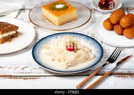 Güllac, Revani, Tulumba und Brot Kadayif Dessert mit Sahne auf einem Holzboden. Ramadan-Süßigkeiten. Traditionelle türkische Köstlichkeiten Stockfoto