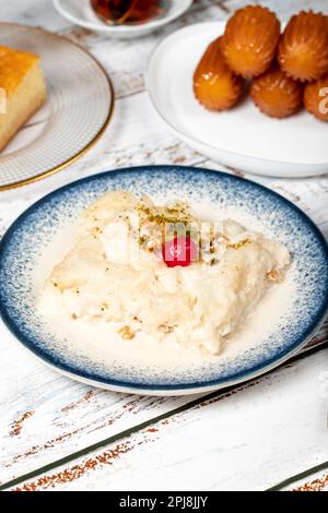 Güllac, Revani, Tulumba und Brot Kadayif Dessert mit Sahne auf einem Holzboden. Ramadan-Süßigkeiten. Traditionelle türkische Köstlichkeiten Stockfoto