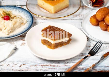 Güllac, Revani, Tulumba und Brot Kadayif Dessert mit Sahne auf einem Holzboden. Ramadan-Süßigkeiten. Traditionelle türkische Köstlichkeiten Stockfoto