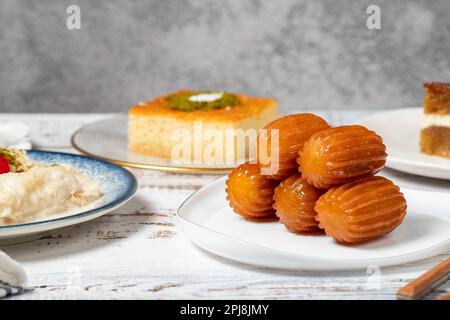 Güllac, Revani, Tulumba und Brot Kadayif Dessert mit Sahne auf einem Holzboden. Ramadan-Süßigkeiten. Traditionelle türkische Köstlichkeiten Stockfoto