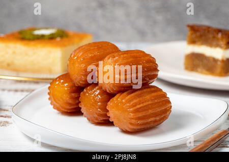 Güllac, Revani, Tulumba und Brot Kadayif Dessert mit Sahne auf einem Holzboden. Ramadan-Süßigkeiten. Traditionelle türkische Köstlichkeiten. Schließen Stockfoto