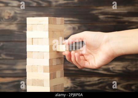 Eine Geschäftsfrau sucht sich das letzte Stück des Holzpuzzels aus und legt es hin. Abstraktes Geschäftskonzept der letzten wichtigen Lösung in der Strategie. Stockfoto