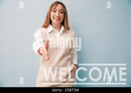 Fröhliche junge Frau, die sich auf hellem Hintergrund die Hand schüttelt, konzentriert sich auf die Hand. Willkommen im Team Stockfoto