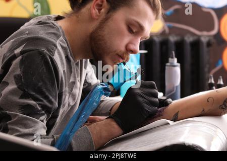 Professioneller Künstler, der im Salon ein Tattoo auf der Hand macht Stockfoto
